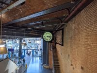 Old style clock attached to a wall in a modern station building.