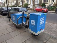 A cargo bike on a residential street with Co Op white and blue branding.